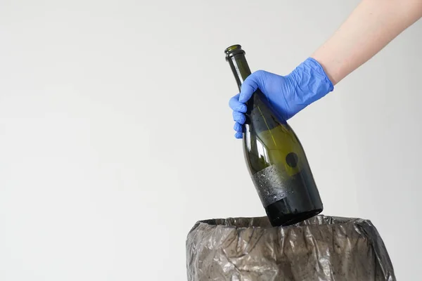 Mulher de luvas a atirar uma garrafa de vidro vazia para o caixote do lixo. Fechar. — Fotografia de Stock