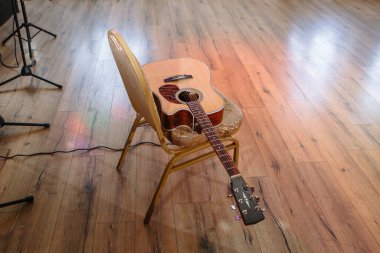 Kahverengi altı telli gitar sandalyede yatıyor..