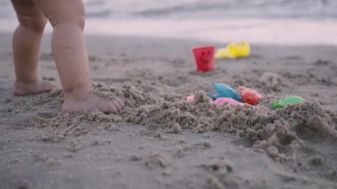 Küçük kız kumsalda kum oynuyor..