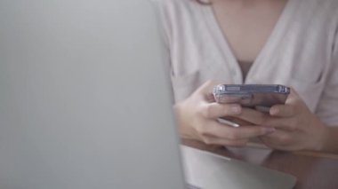 Kahve dükkanında akıllı telefondan yazan genç bir kadın..