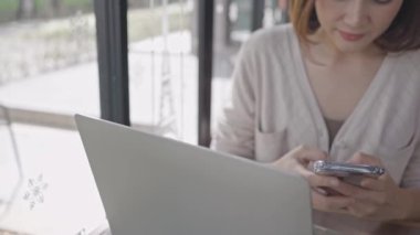 Akıllı telefon kullanan genç bir kadın internetteki sosyal medyayı kontrol ediyor, mutlu bir gülümseme..