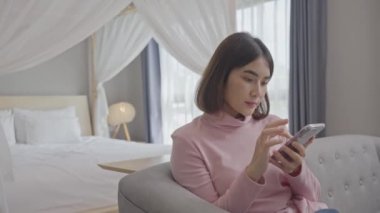 Rahat genç bir kadın akıllı telefon kullanarak sosyal medyada sörf yapıyor, haberleri kontrol ediyor, mobil oyunlar oynuyor ya da koltukta oturmuş mesaj yazıyor..