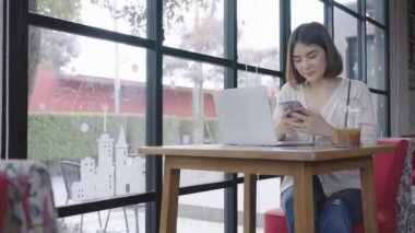 Akıllı telefon kullanan genç bir kadın internetteki sosyal medyayı kontrol ediyor, mutlu bir gülümseme..