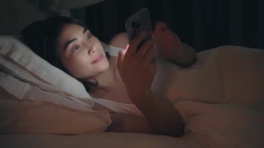 Kadın geceleri uyumadan önce yatağın üzerinde telefon kullanıyor..