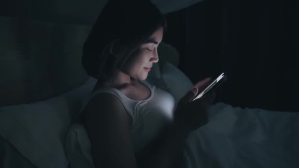 Mulher está usando telefone na cama antes de dormir à noite. — Vídeo de Stock