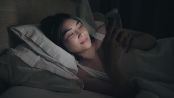 Žena posílá vzkazy na mobil a leží na posteli. — Stock video