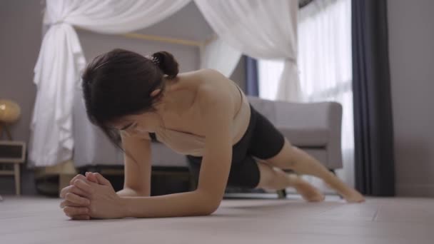 Молода здорова жінка тренується вдома, займається фізичними вправами, підходить, робить йогу, концепція домашньої фітнесу . — стокове відео