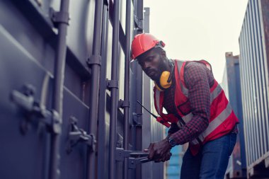 African-American workers are opening containers for inspection and check that repairs have been completed in containers.