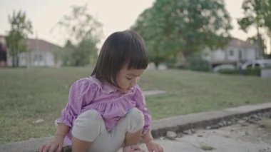 Küçük kız bahçede oturmuş, taş oynuyor. Mutlu kız bebek.