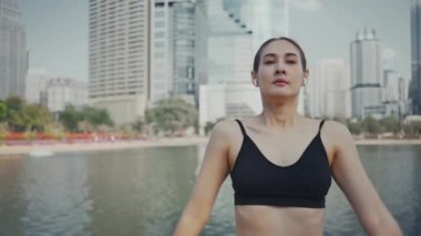 Şehirde koşmadan önce kablosuz kulaklık takan ve kaslarını esneten sporcu kadın ısınma egzersizi yapıyor..