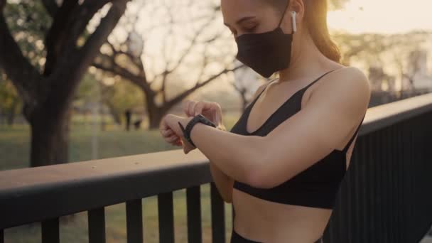 戴着防护面罩的女人为跑步准备了健康的智能手表 女运动员检查手表装置 — 图库视频影像