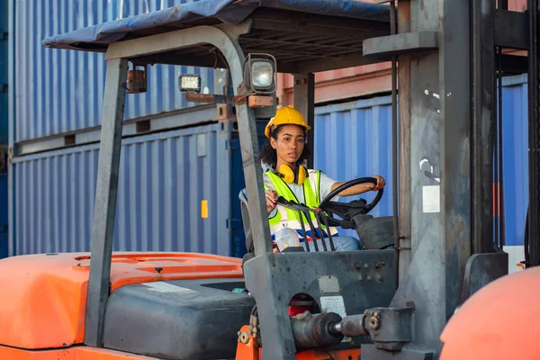 Kadın ustabaşı konteynır deposunda forklift kullanıyor. Rıhtımda nakliye.