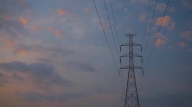 Güç iletim hatları. Elektrik direkleri ve telleri. Gündoğumu arka planında yüksek voltajlı elektrik hatları.