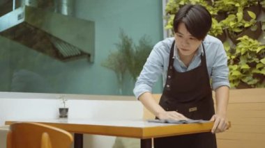 Bir bayan restoran çalışanı ya da genç girişimci müşterileri karşılamak için yemek masasını temizler..