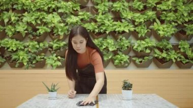 Bir bayan restoran çalışanı ya da genç girişimci müşterileri karşılamak için yemek masasını temizler..