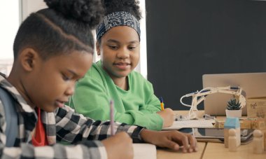 Student in international preschool writing a book together in Elementary School Class, Pupils enjoying studying in classroom.