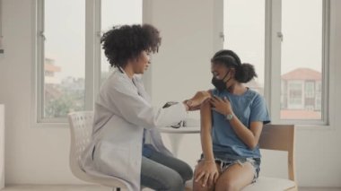 Afrikalı Amerikalı doktor, aşılandıktan sonra çocuğun omzuna alçı uyguluyor. Grip ya da salgın hastalığa karşı aşı kolları açmak ve aşı kavramı.