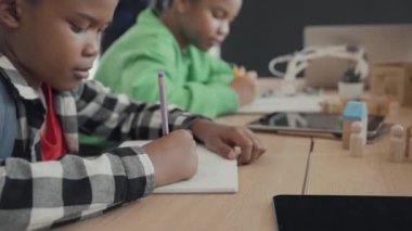 Uluslararası anaokulundaki öğrenci ilkokul sınıfında birlikte kitap yazıyor. Öğrenciler sınıfta ders çalışmaktan zevk alıyor..