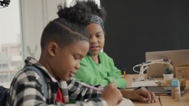 Uluslararası anaokulundaki öğrenci ilkokul sınıfında birlikte kitap yazıyor. Öğrenciler sınıfta ders çalışmaktan zevk alıyor..