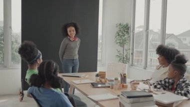 Afrikalı Amerikalı kız öğrenci kendini sınıfa özgüvenle tanıtıyor..