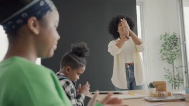 Afrika kökenli Amerikalı öğrencilerin ve öğretmenlerin birlikte aktiviteler yaptığı bir sınıf. Öğretmen çocuklara çeşitli öğretiyor, rehberlik ediyor ve onlarla konuşuyor..