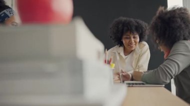 Afrika kökenli Amerikalı öğrencilerin ve öğretmenlerin birlikte aktiviteler yaptığı bir sınıf. Öğretmen çocuklara çeşitli öğretiyor, rehberlik ediyor ve onlarla konuşuyor..