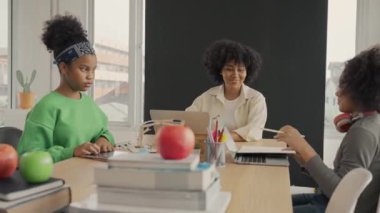 Afrika kökenli Amerikalı öğrencilerin ve öğretmenlerin birlikte aktiviteler yaptığı bir sınıf. Öğretmen çocuklara çeşitli öğretiyor, rehberlik ediyor ve onlarla konuşuyor..