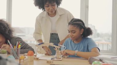 Afrika kökenli Amerikalı öğrencilerin ve öğretmenlerin birlikte aktiviteler yaptığı bir sınıf. Öğretmen çocuklara çeşitli öğretiyor, rehberlik ediyor ve onlarla konuşuyor..