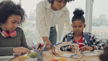 Afrika kökenli Amerikalı öğrencilerin ve öğretmenlerin birlikte aktiviteler yaptığı bir sınıf. Öğretmen çocuklara çeşitli öğretiyor, rehberlik ediyor ve onlarla konuşuyor..