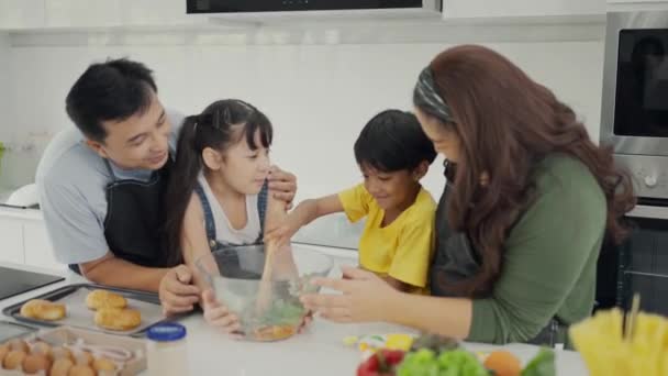 快乐的家庭妈妈爸爸和孩子们一起做饭 父母教孩子们的女儿做新鲜蔬菜沙拉和羊角面包 一起在现代厨房里准备健康食品 — 图库视频影像