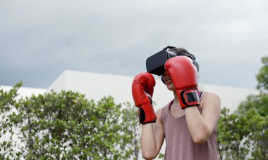 Boks yapmak için VR kulaklık takan genç bir kadın, simülasyon dünyasında boks yapmak için aerobik eğitimi alan bir kadın..