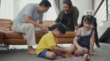 Mutlu aile, anne ve baba kanepede kedi oynuyorlar, sevimli çocuklar yerde bloklarla oynuyorlar, birlikte eğleniyorlar..