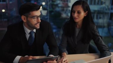 İki meslektaş, bilgisayar ya da not defteri kullanarak pazarlamayı analiz eden verileri tartışıyor iş arkadaşlarıyla ofis masasında oturmalarına yardımcı oluyorlar..