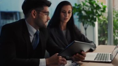 İki meslektaş, bilgisayar ya da not defteri kullanarak pazarlamayı analiz eden verileri tartışıyor iş arkadaşlarıyla ofis masasında oturmalarına yardımcı oluyorlar..