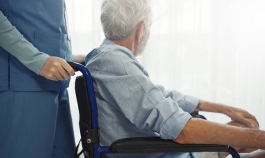 Nurse putting wheelchair with senior man  window. Unhappy senior man having geriatric or depression disease. Therapist taking care, giving support and empathy.