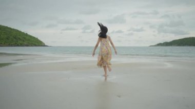 Sahilde koşan Asyalı bir kız, yaz tatilinde dürüst mutluluk kavramı..