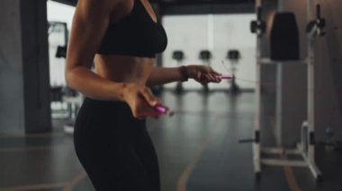 Young woman working on her fitness, skipping with a jump rope at the gym.