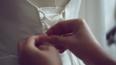 close-up of hands tying shoelaces on wedding dress, preparing for the wedding.