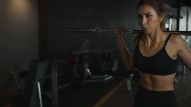 Sportwoman exercising with barbell in fitness class. Workout woman in gym with barbell.