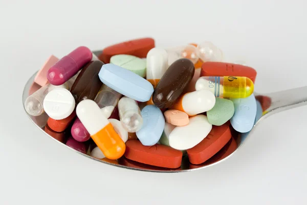 Colourful pills on a spoon — Stock Photo, Image