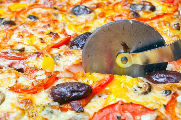 Cutter cuts a pizza — Stock Photo, Image