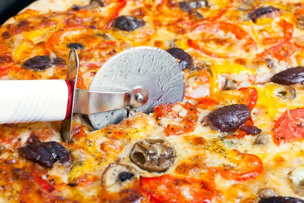 Cutter snijdt een pizza — Stockfoto