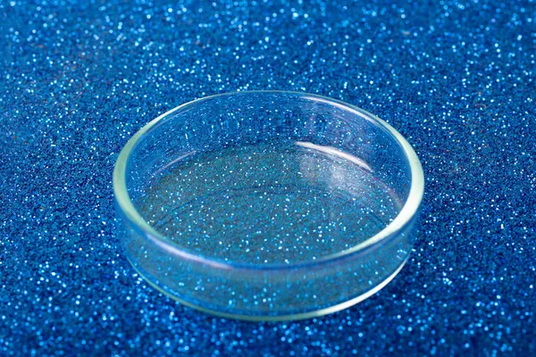 Prázdná Petriho miska na modrém třpytivém pozadí. — Stock fotografie