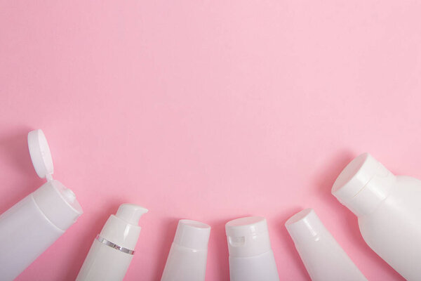 Вид сверху на контейнеры для косметики на розовом фоне с отрицательным пробелом..