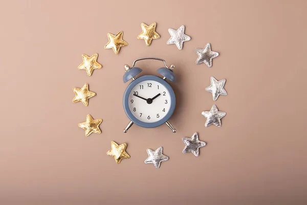 Alarm clock with golden and silver stars around it.Concept of the healthy dreams and circadian rhythms.