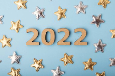 Mavi arkaplanda 2022 ahşap numaraların üst görüntüsü. Altın ve gümüş yıldızlar. Şenlikli bir konsept..