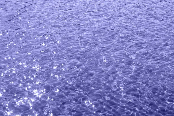 Yüzeyinde güneş ışınları olan deniz dalgalarının soyut arkaplanı. 2022 'nin modaya uygun rengi..