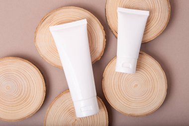 Tahta dilimlerdeki boş kozmetik tüplerinin üst görüntüsü. Dünya tonları, çevre dostu kavram..