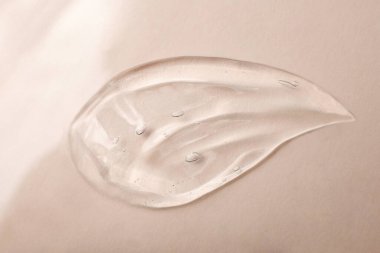 Sıvı kozmetik jelin üst görüntüsü, damlaya benziyor. Pastel bej arka plan. Kozmetik modelleme kadar iyi..