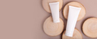 Tahta dilimlerdeki boş kozmetik tüplerinin üst görüntüsü. Dünya tonları, çevre dostu kavram. Kopya alanı olan büyük afiş..
